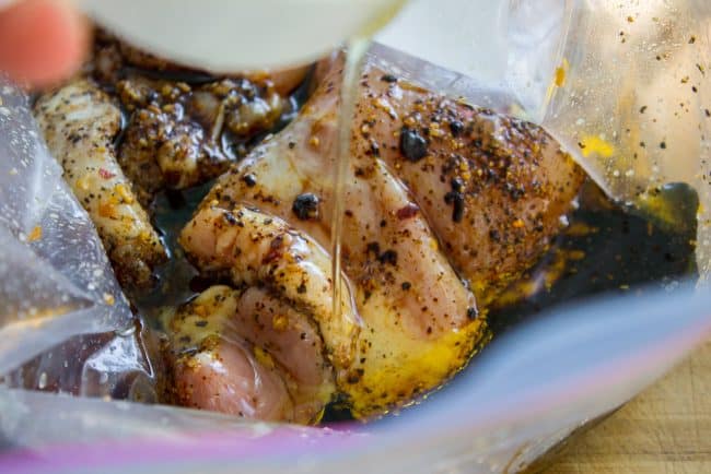 pouring a marinade on chicken breasts.