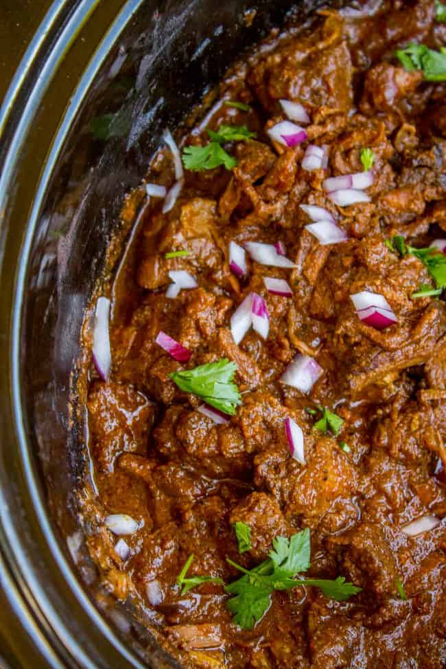 beef curry in a slow cooker with red onion and cilantro. 