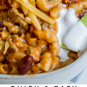Close-up of chili mac and cheese topped with shredded cheese, sour cream, and green onions. Text at the bottom reads: âQuick & Easy Chili Mac & Cheese â The Food Charlatan.â Perfect for a quick dinner.
