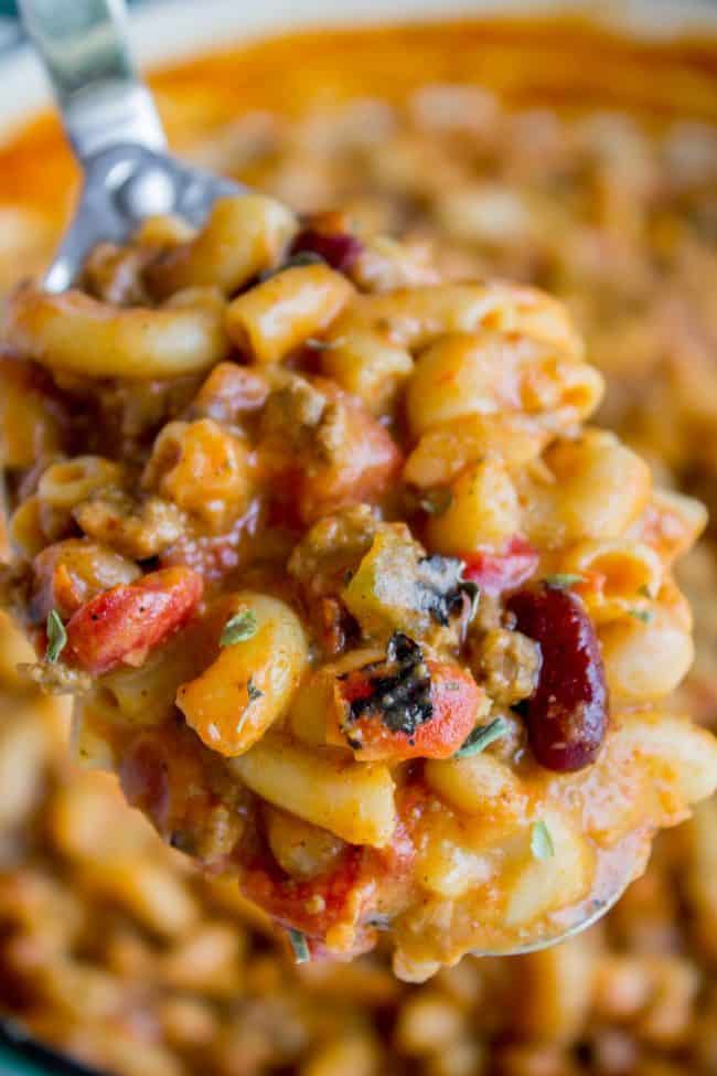 chili mac and cheese being lifted with a metal serving spoon. 