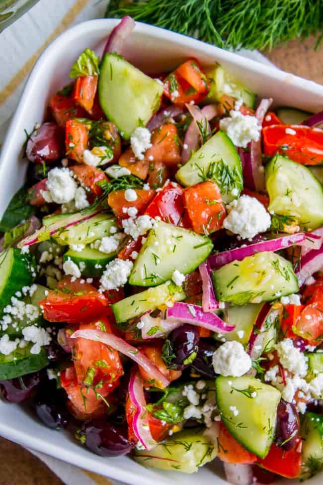 Greek tomato cucumber salad with feta cheese in a white bowl. 