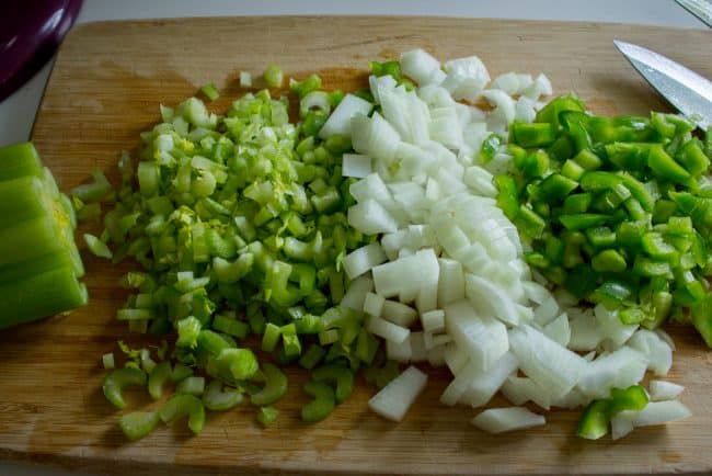 chopped onion and celery on a wooden cutting board.