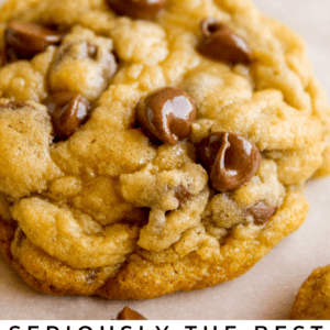 Close-up of a thick, golden-brown chocolate chip cookie with gooey, melted chocolate chips on top, placed on a white surface. Text at the bottom reads, Seriously delicious chocolate chip cookies.