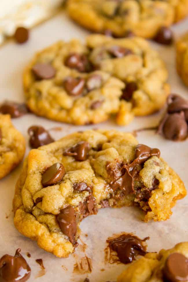 chocolate chip cookies with a big bite taken out of one and chips melting on parchment paper.