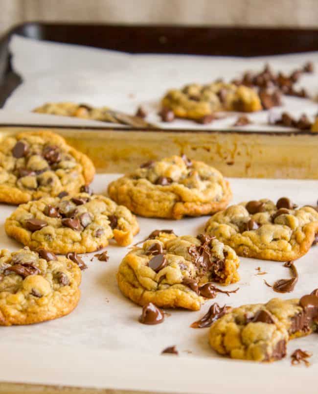 the aftermath of a chocolate chip cookie photo shoot with bites taken out of multiple cookies and chocolate smeared everywhere. 