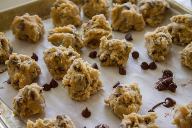 chocolate chip cookie dough in balls on a parchment lined baking sheet.