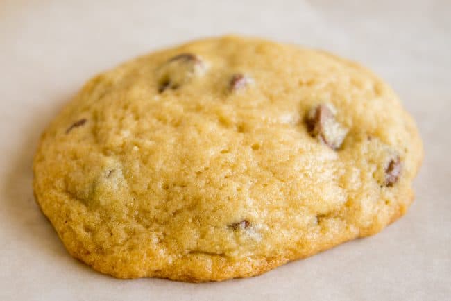 a freshly baked chocolate chip cookie on parchment paper.