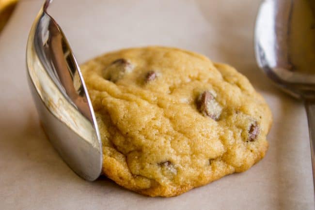using a spoon to smoosh the edge of a chocolate chip cookie. 