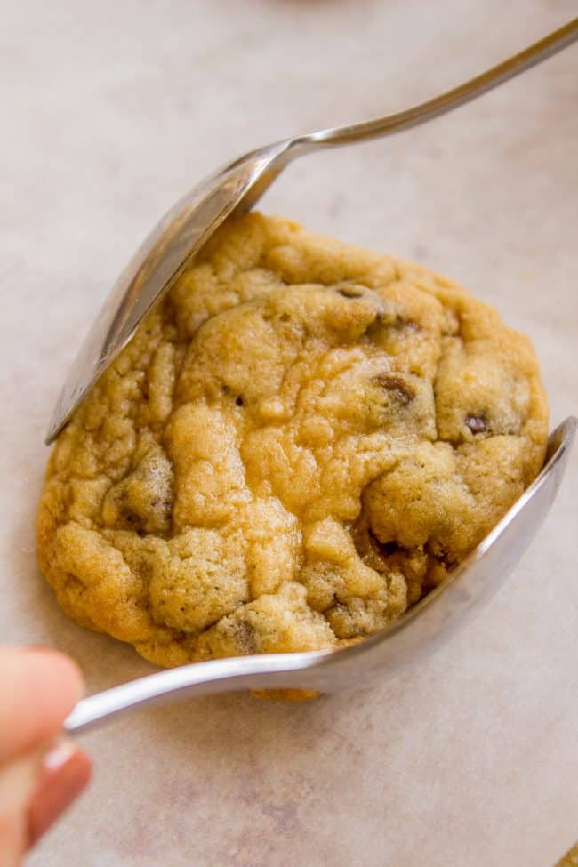 using two spoons to smoosh the edges of a warm chocolate chip cookie. 