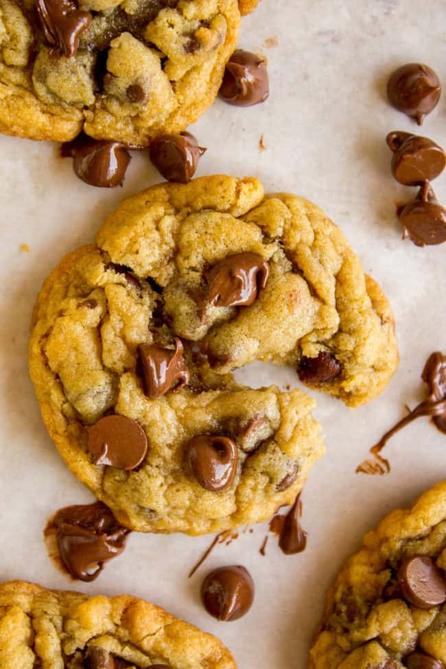 chocolate chip cookie gently tearing and chips melting on parchment paper.