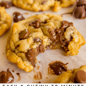 chocolate chip cookies on parchment paper, one with a big bite taken out of it.