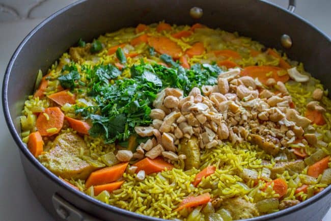 adding cilantro and cashews to chicken biryani. 