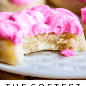 Soft Sugar cookie with pink frosting and a bite taken out of it on a white plate