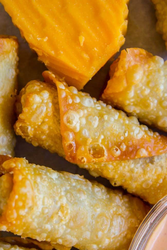 cheeseburger egg rolls near a block of cheddar.