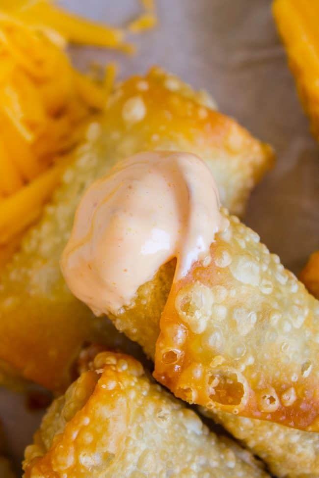 cheeseburger egg rolls with the end of one dipped in fry sauce.