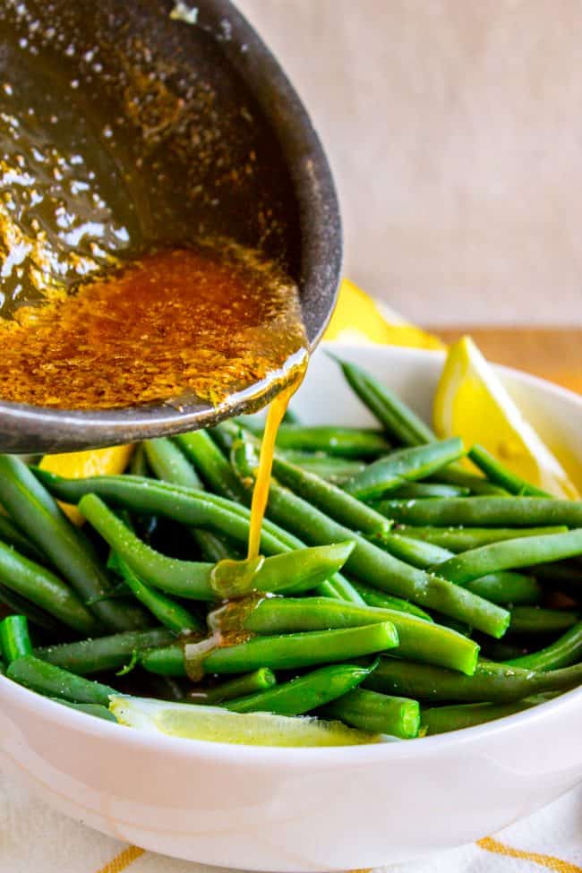 pouring browned butter over blanched green beans.