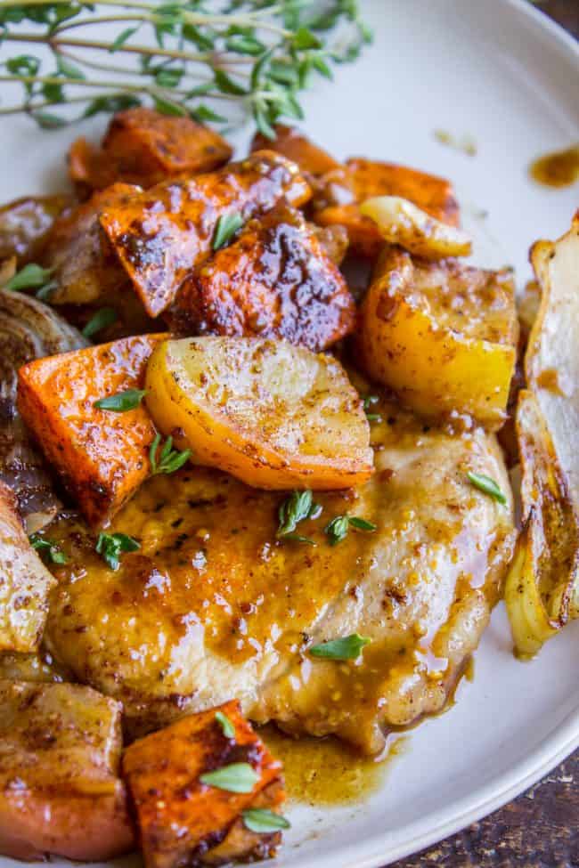 a plate of pork chops with veggies and apples.