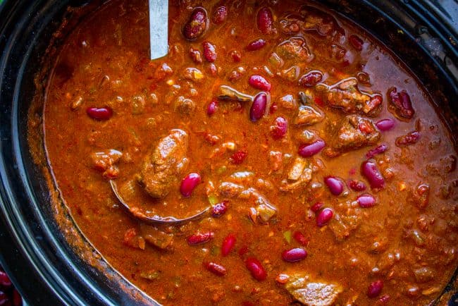 chili with a metal ladle in a crockpot shot from overhead.