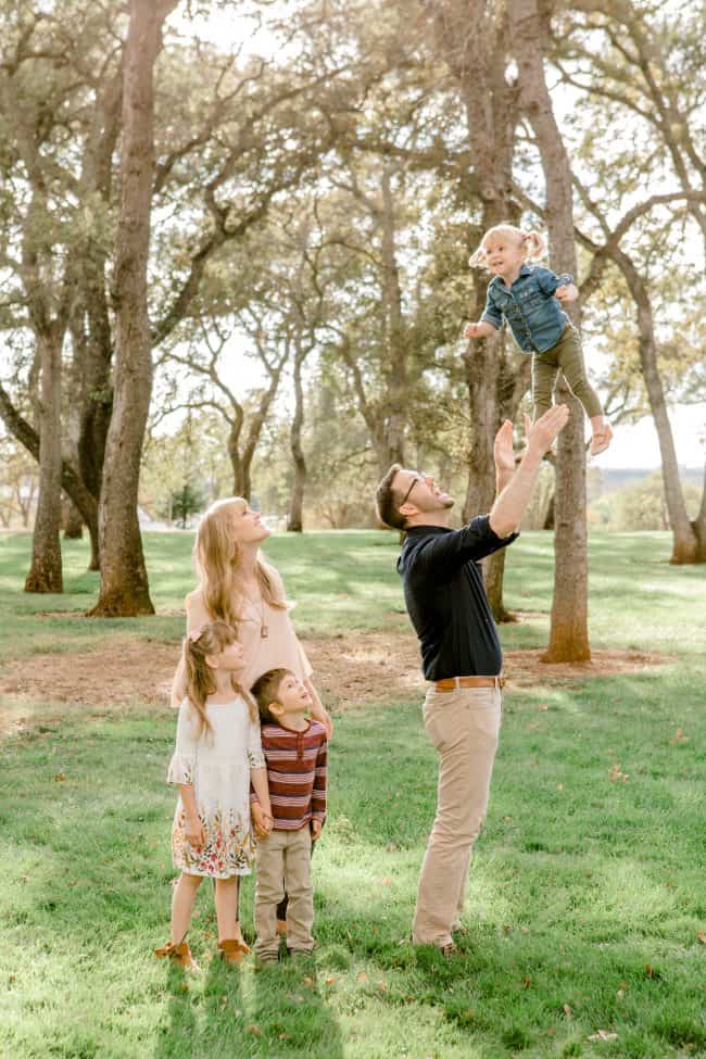 family photo with dad throwing little girl in the air.