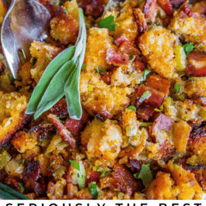 A close-up of cornbread stuffing mixed with crispy bacon, herbs, and vegetables in a baking dish, with two serving spoons and a sprig of fresh sage on top. The text reads: Seriously Delicious Cornbread Stuffing.