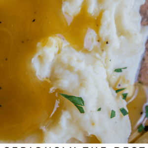 Close-up of creamy mashed potatoes topped with golden gravy and garnished with chopped herbs. Text at the bottom reads: “Seriously Creamy Mashed Potatoes – The Food Charlatan.”.