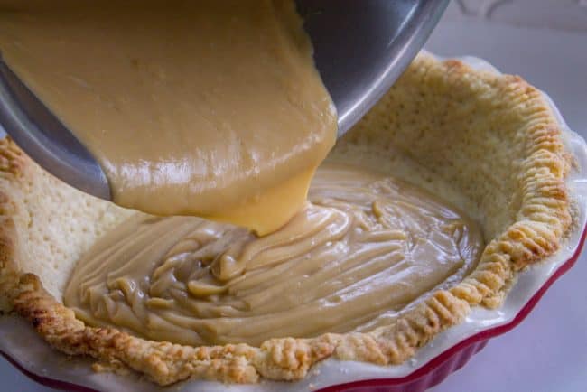 filling a blind baked pie crust with butterscotch filling.