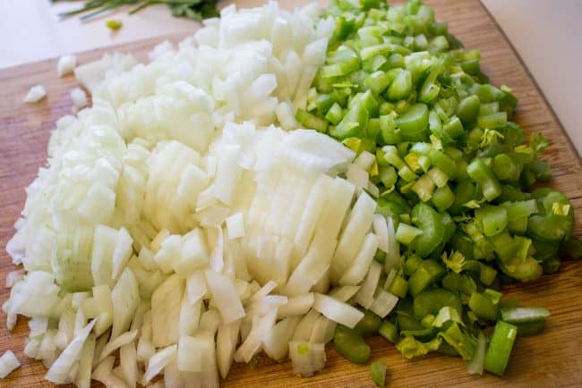 chopped onions and peppers on a wooden cutting board.