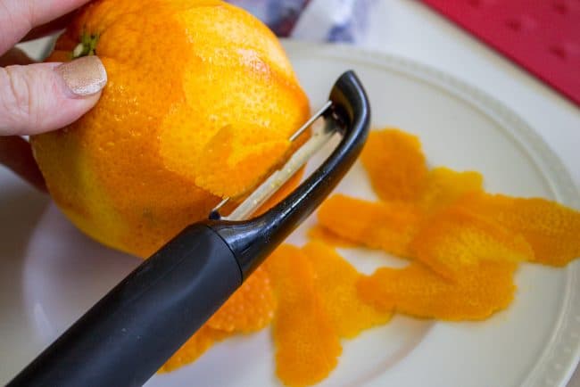 peeling an orange onto a white plate.