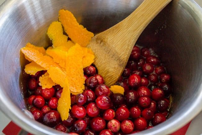 stirring orange peel into cranberries in a pot.