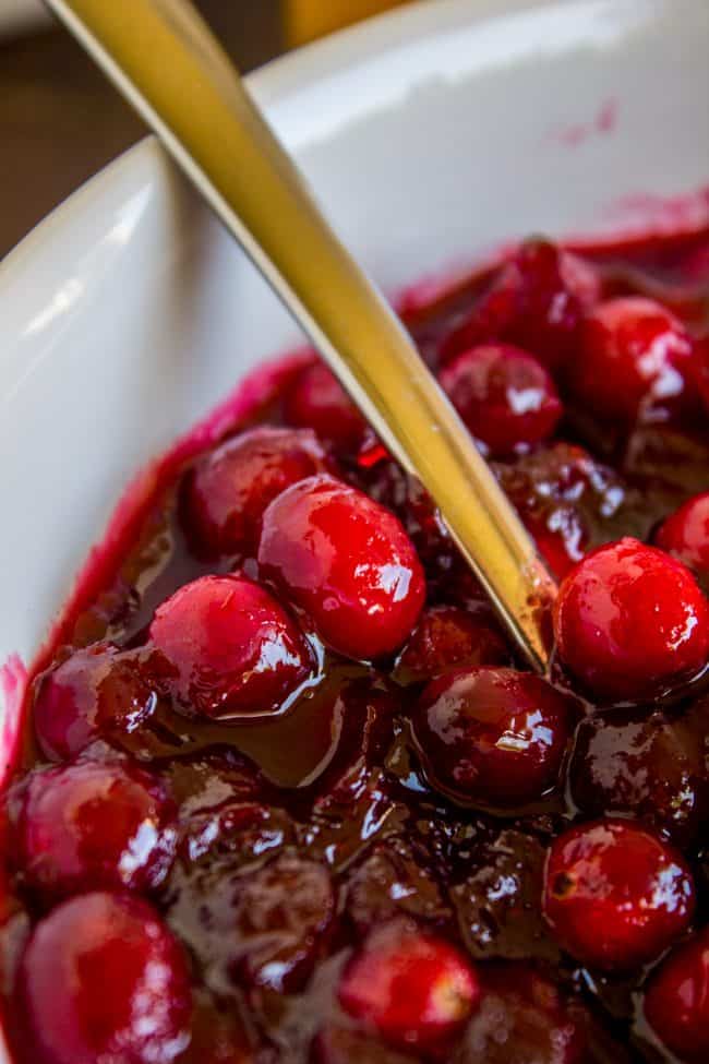 homemade cranberry sauce in a white bowl with a gold spoon.