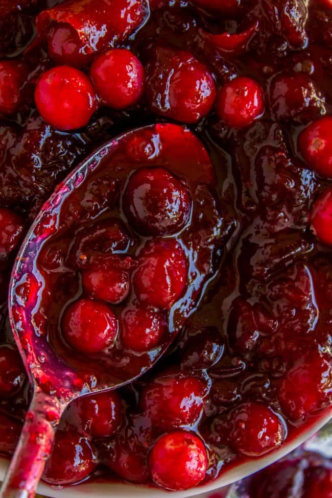 a spoon lifting cranberry sauce from a bowl.