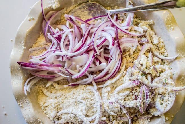 battering red onion slices in a pie pan with a metal spoon. 