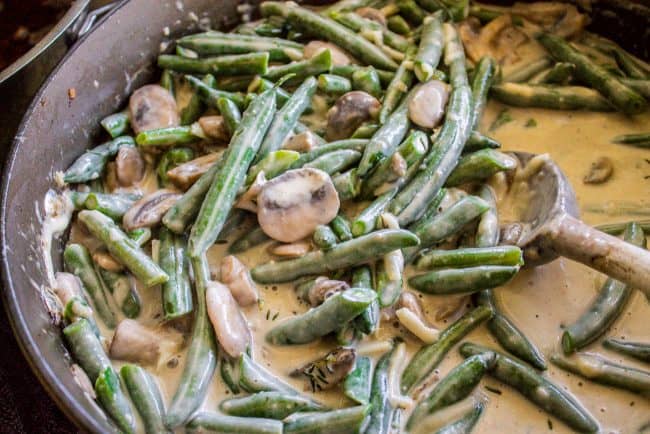 a mixture of green beans, parmesan cheese, and creamy mushroom sauce in a skillet.