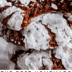 A close-up of stacked chocolate crinkle cookies, dusted with powdered sugar. The cookies appear soft and rich, with a cracked surface, and the text below reads, Chocolate Crinkle Cookies.