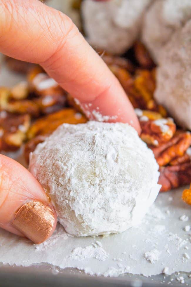 close up of snowball cookie with pecans in the background.