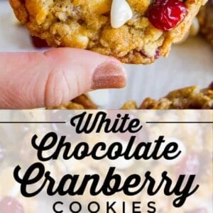 Close-up of white chocolate cranberry cookies, adorned with white chocolate chips and dried cranberries. One cookie is held up to show its soft texture; others are scattered on a light surface. Text reads White Chocolate Cranberry Cookies.
