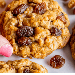 hand lifting an oatmeal raisin cookie from a cookie sheet.
