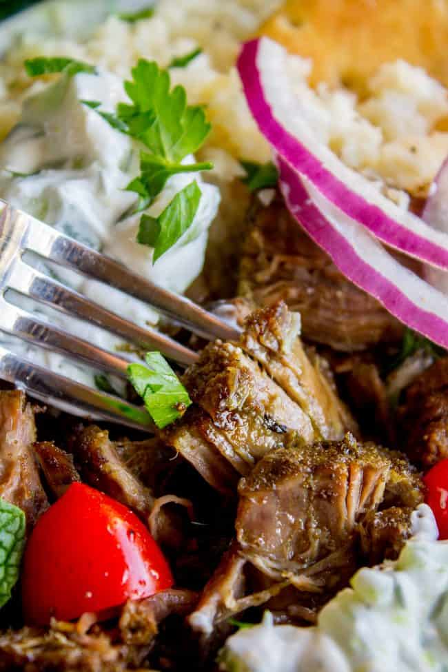 a forkful of Greek gyro beef with tzatziki sauce, cauliflower rice, fresh veggies, and herbs.