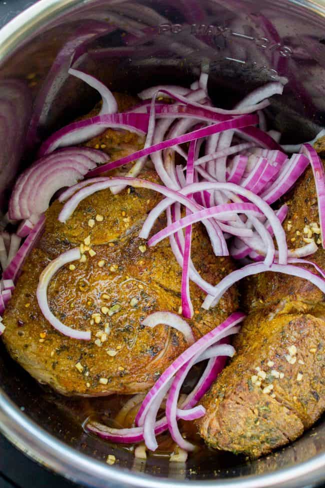 beef roast, browned and rubbed with spices, in the Instant Pot with sliced red onions.