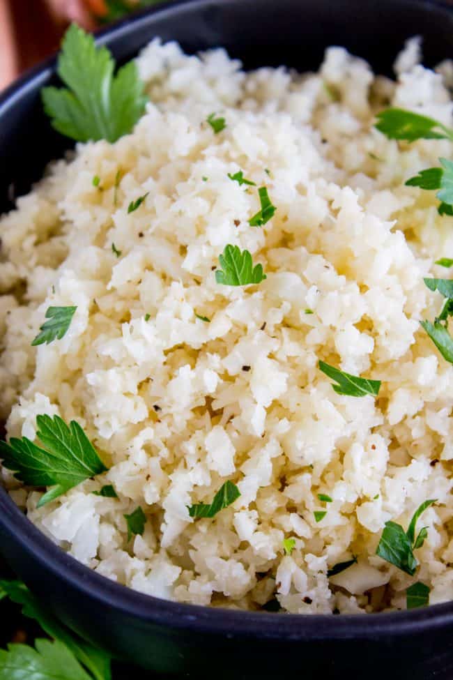 cauliflower rice garnished with cilantro in a black bowl.