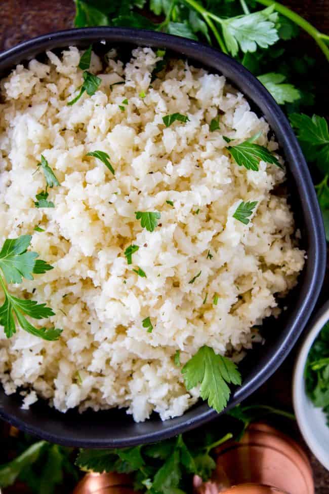 cauliflower rice garnished with cilantro in a black bowl.