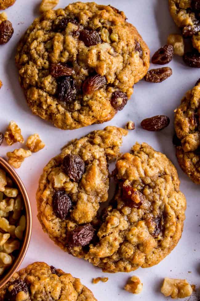 chewy oatmeal raisin cookies on parchment paper with raisins and walnuts.