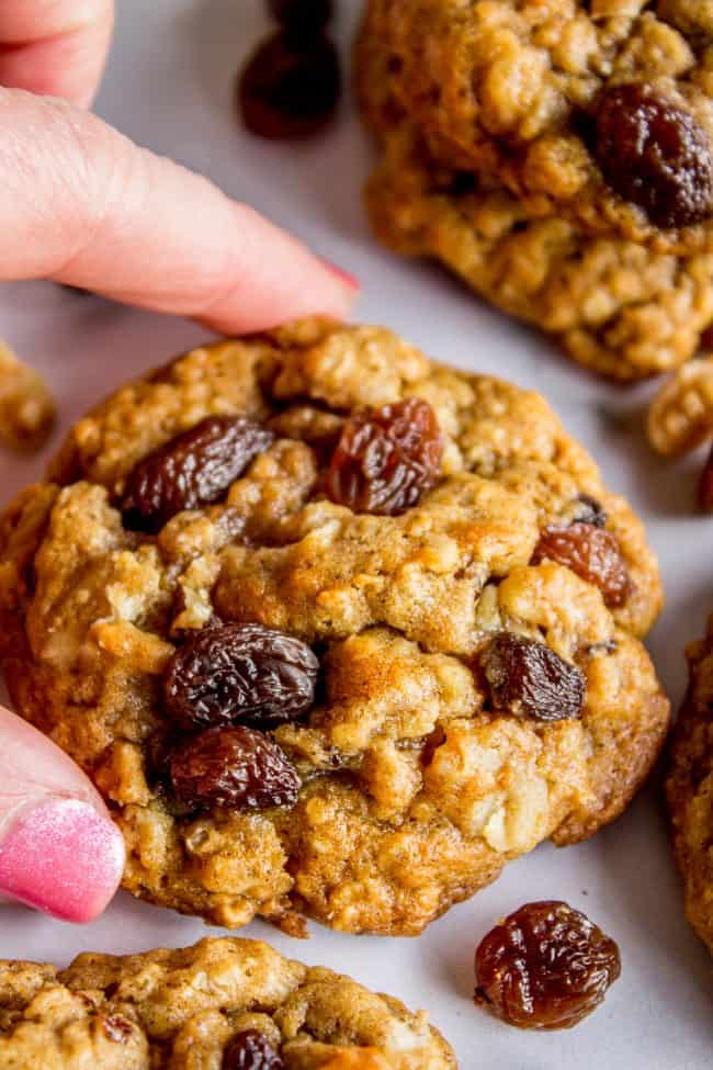 hand picking up a soft and chewy oatmeal raisin cookie.