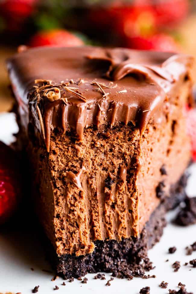 chocolate cheesecake with a forkful removed on a white plate.