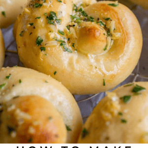 Golden brown garlic knots topped with chopped parsley and garlic butter, arranged closely together on a cooling rack. Text overlay reads: Classic Garlic Knots with parsley & garlic butter - The Food Charlatan.