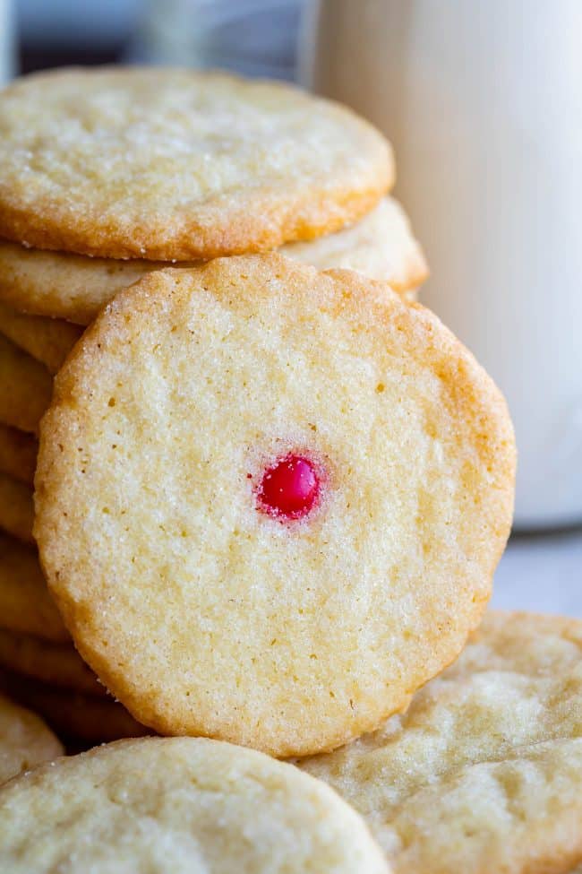 a stack of thin sugar cookies, one with a red hot in the center.