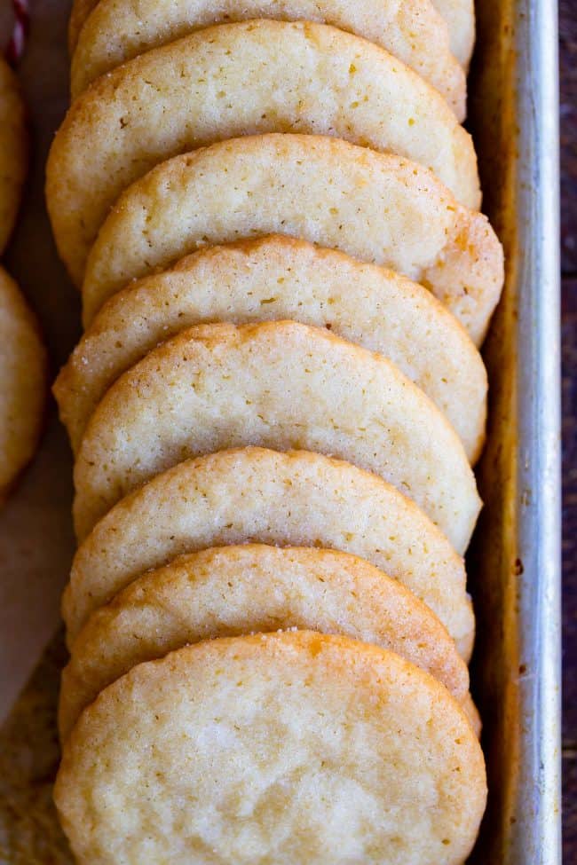 thin crunchy sugar cookies in a row on a baking sheet.