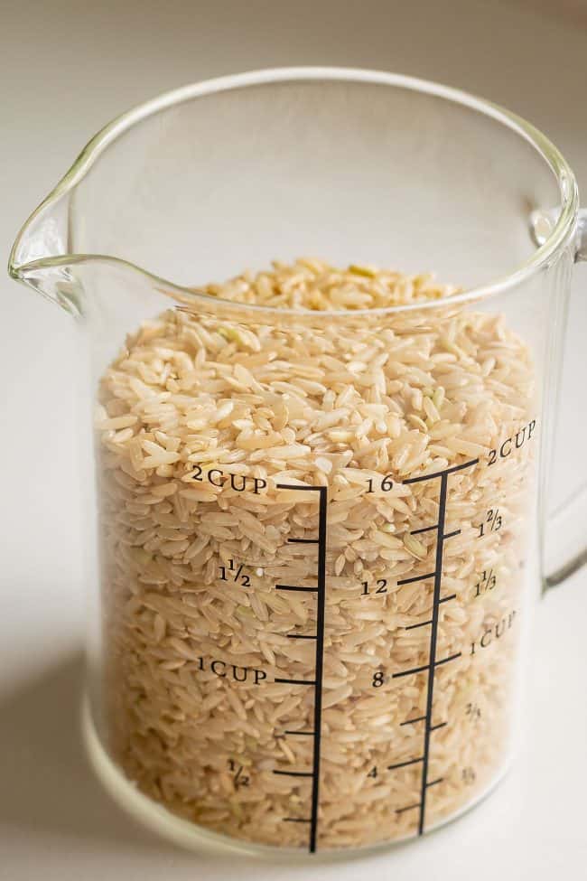 a 2 cup measuring cup with uncooked brown rice.