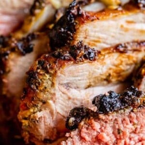 Close-up of juicy, sliced roast pork and roast leg of lamb, both with a seasoned, crispy crust and tender, slightly pink interiors.