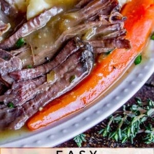 Close-up of a plate with shredded crock pot roast, sliced carrots, and mashed potatoes covered in gravy. Text at the bottom reads: Easy Fall-Apart Pot Roast Slow Cooker.